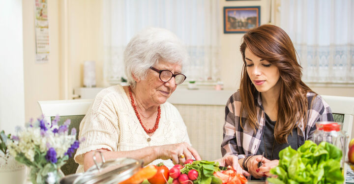 Ältere Frau schneidet mit junger Frau Gemüse